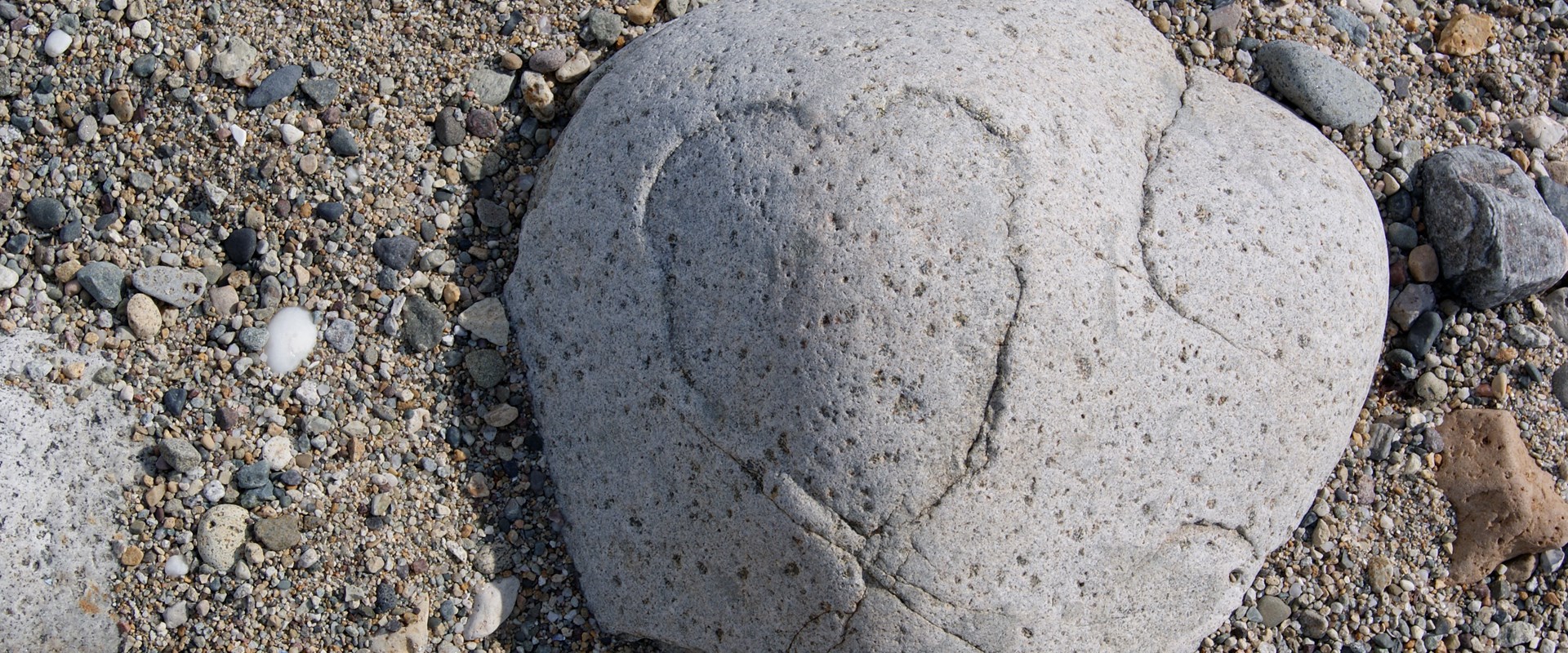 A stone on a beach with a heart shape etched naturally by the erosion of weather