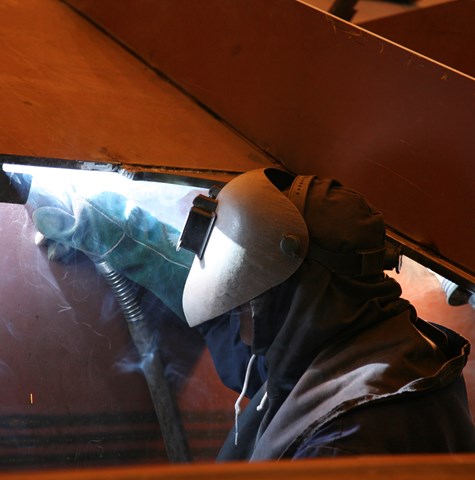 An image of a welder welding steel on the underside of a vessel