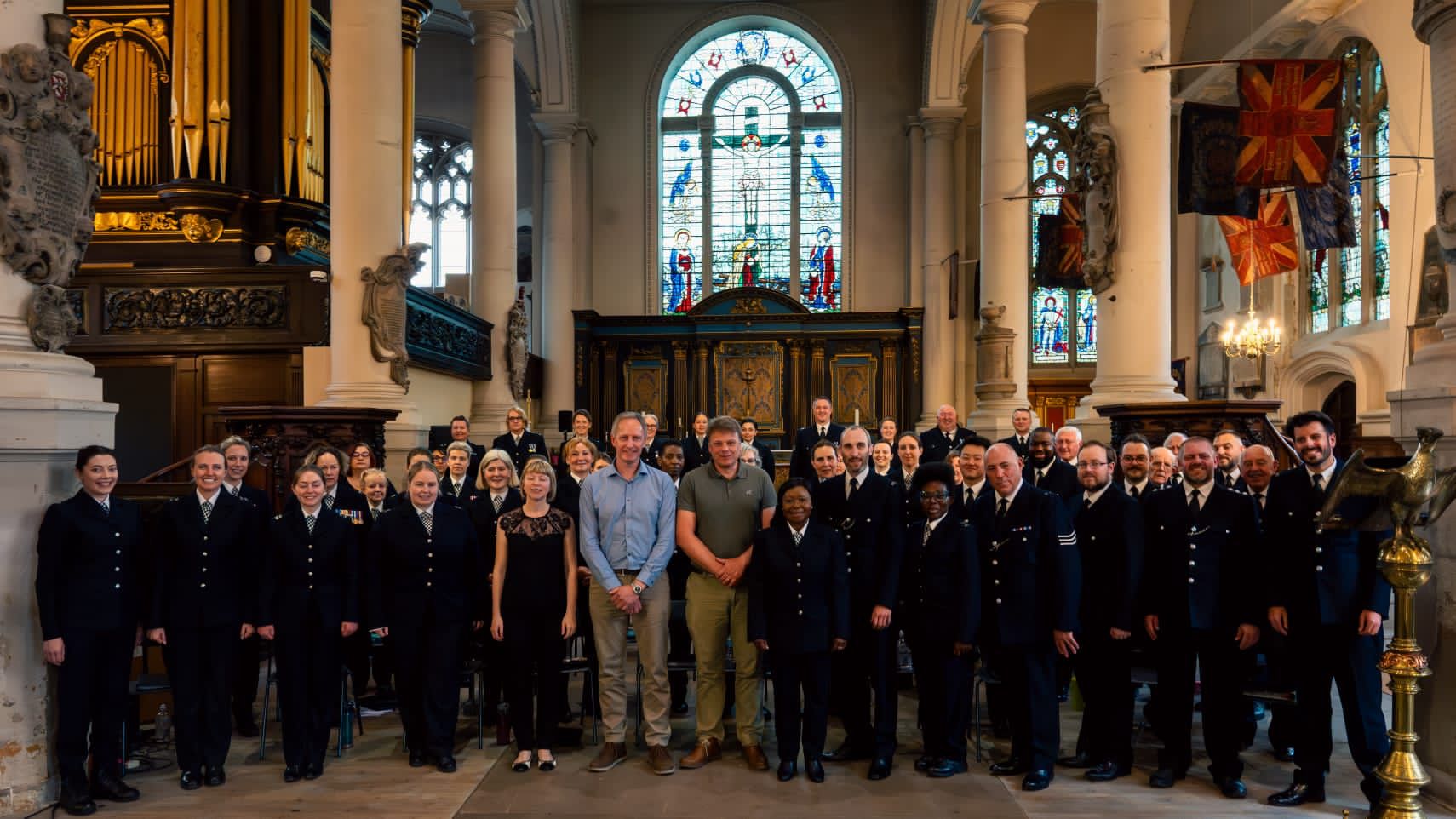 The Metropolitan Police Choir with Alan Hodgson and Christian Ellis standing in a church