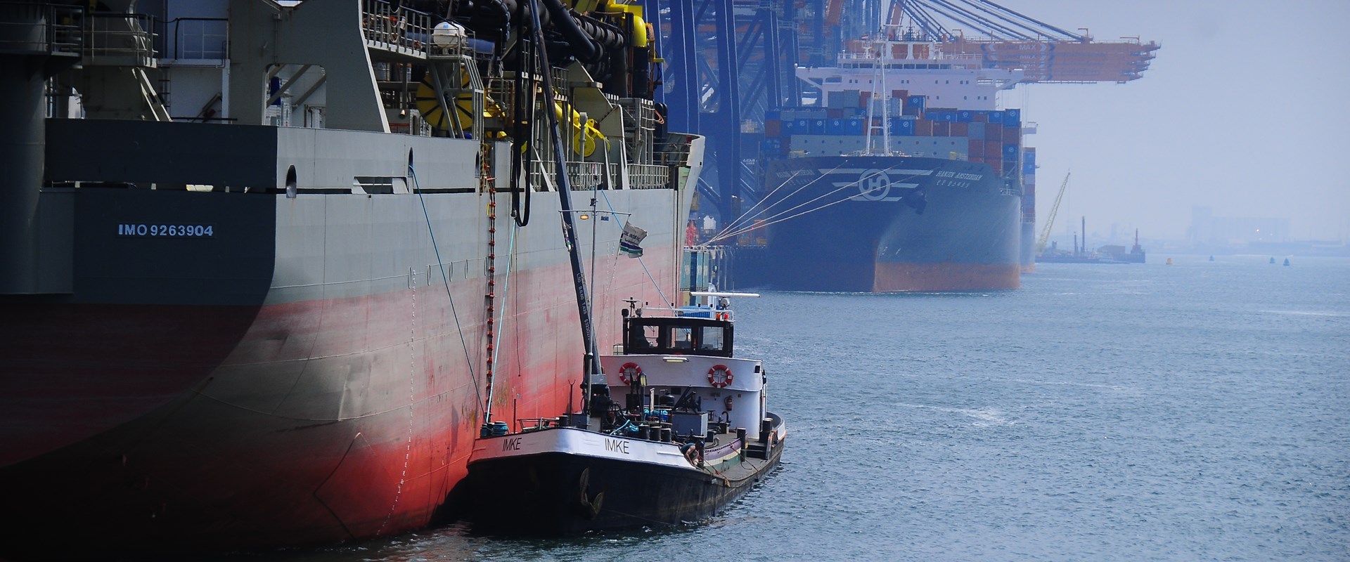 A tug boat alongside a larger vessel in a harbour