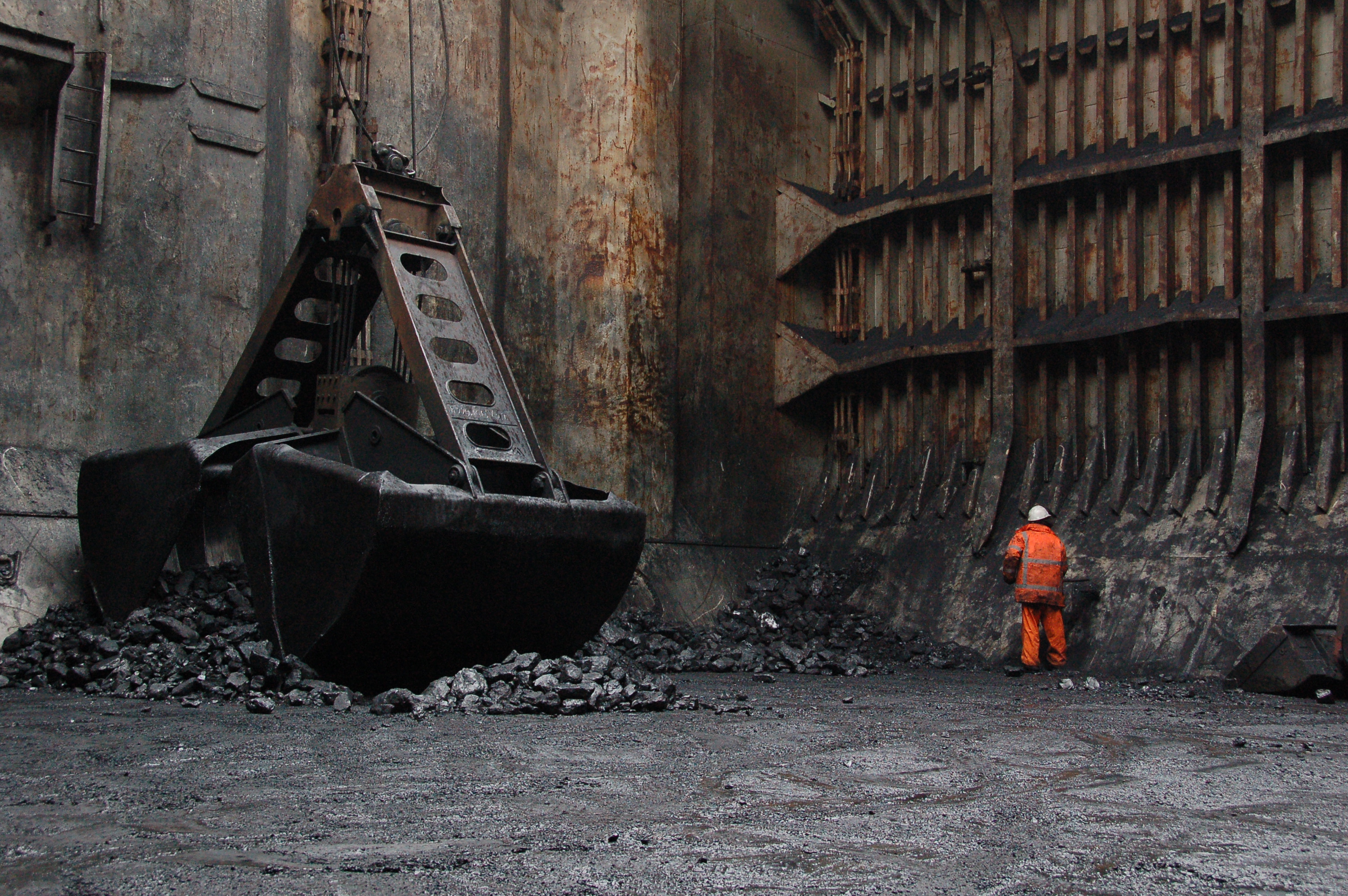 A picture of a man working in the cargo hold of a ship sweeping up material that has spilled