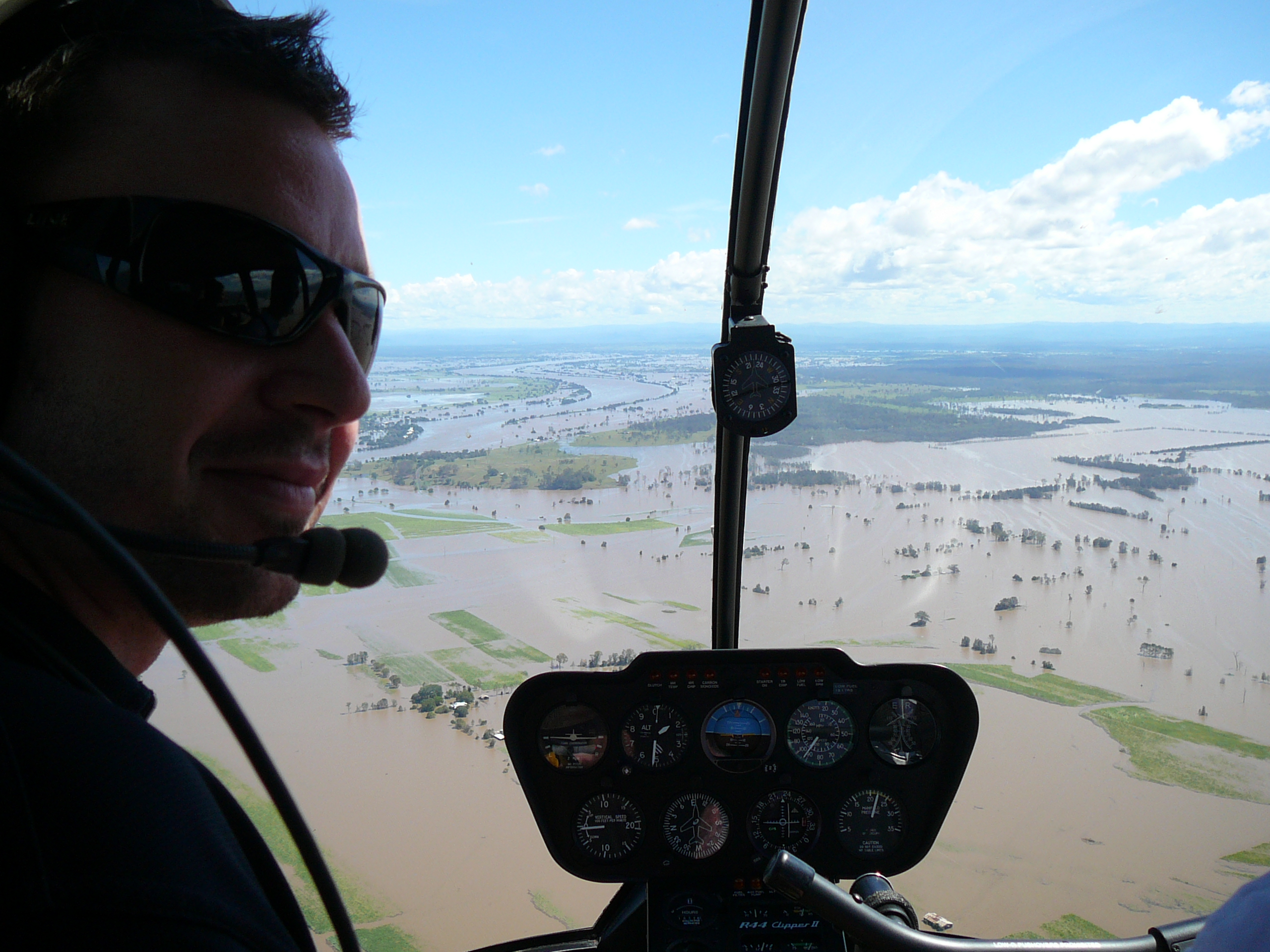 An environmental engineer in a helicopter looking out over a flooded area of land