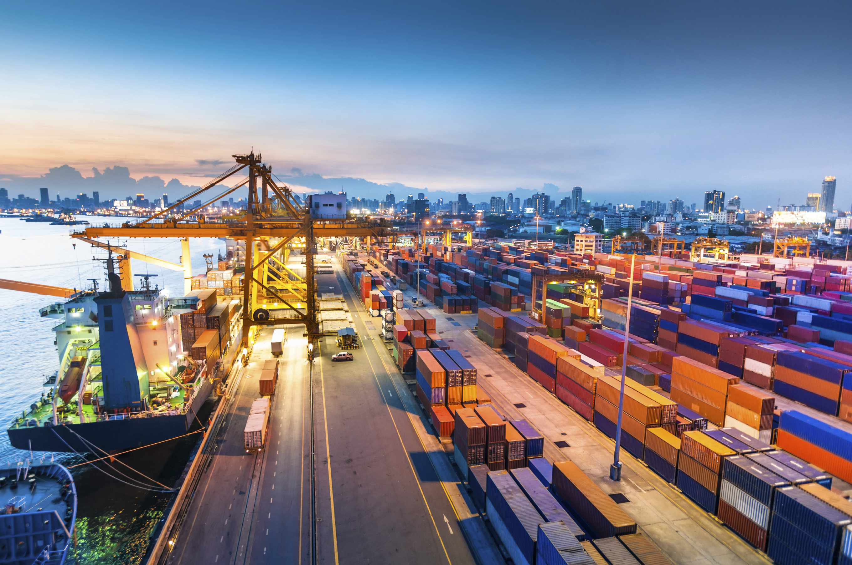 A photograph of a container port with lots of containers and a few vessels docked