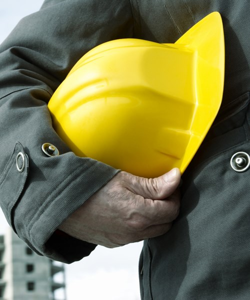 Engineer holding a helmet for workers security on background of building construction