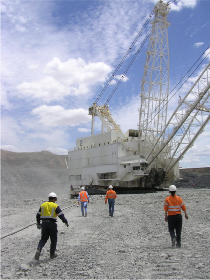 Men in high-vis clothing walking towards a mining machine