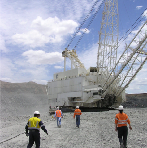 Men in high-vis clothing walking towards a mining machine