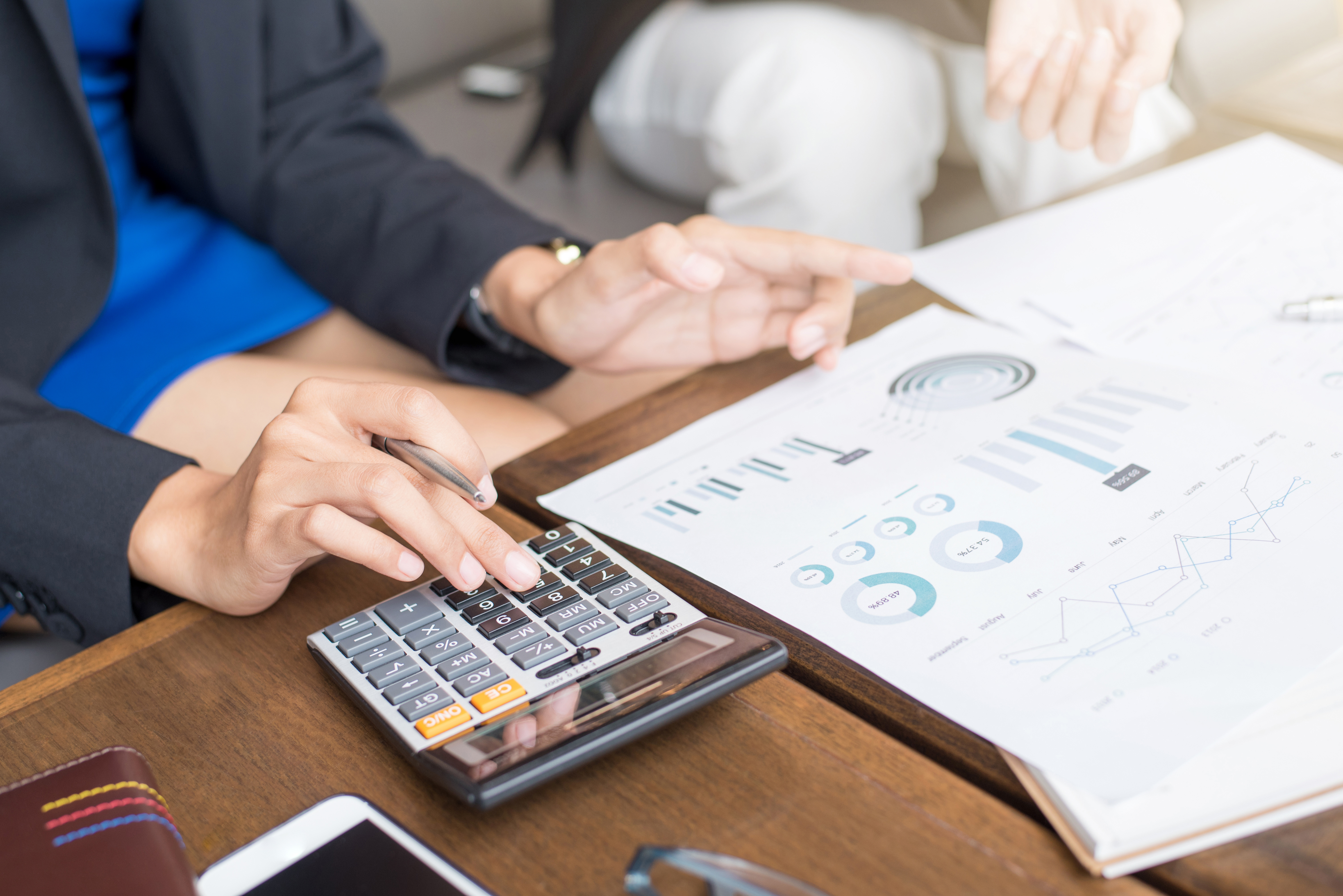 Two people reviewing pages with graphs with one using a calculator