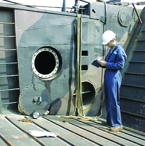 An image of a surveyor writing a report while onboard a damaged vessel