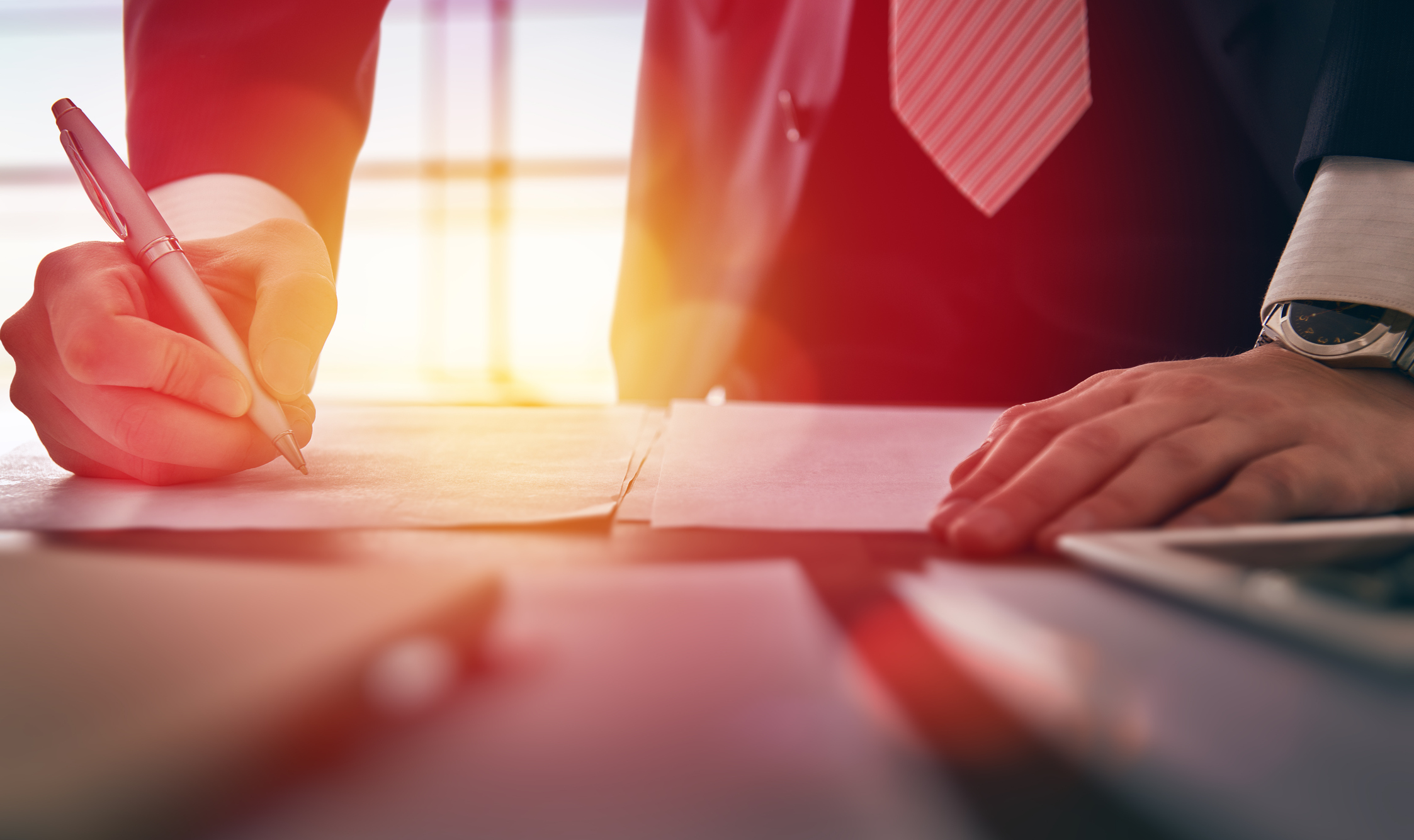 Image of somebody writing on a plan on a desk