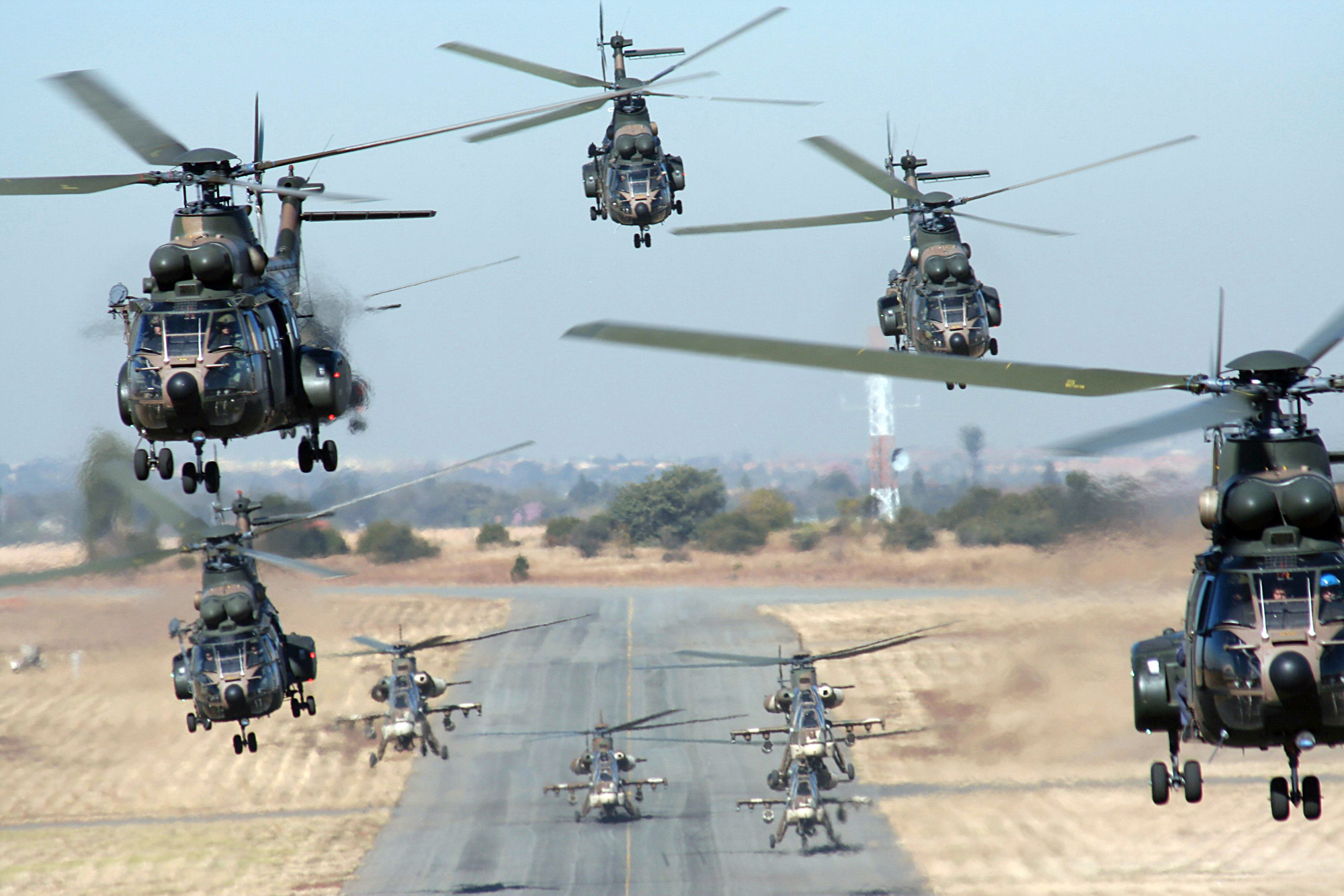 Fleet of helicopters taking to the skies over a runway