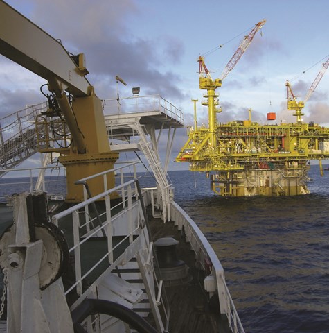 An image of an offshore oil and gas platform at sea with a vessel bow in the foreground