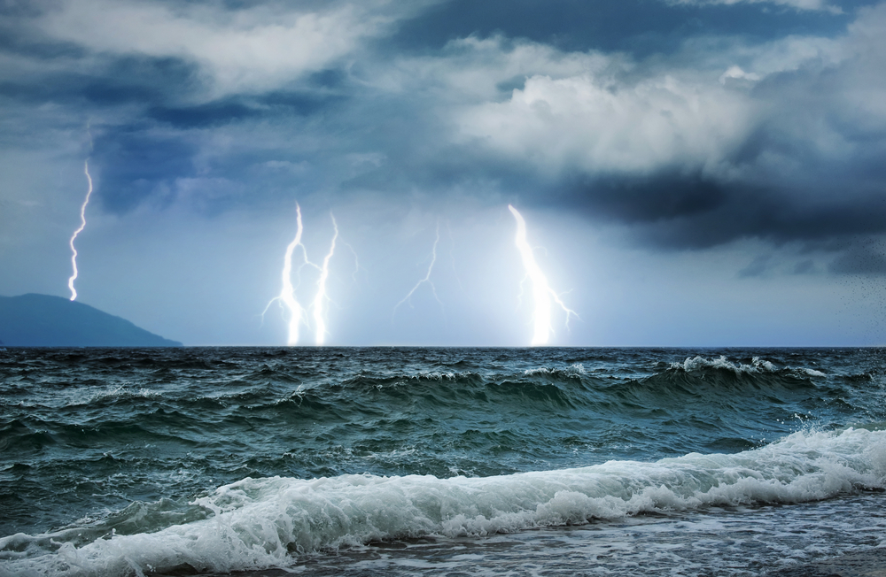 An image of a storm sea with waves and thunder and lighting in the background