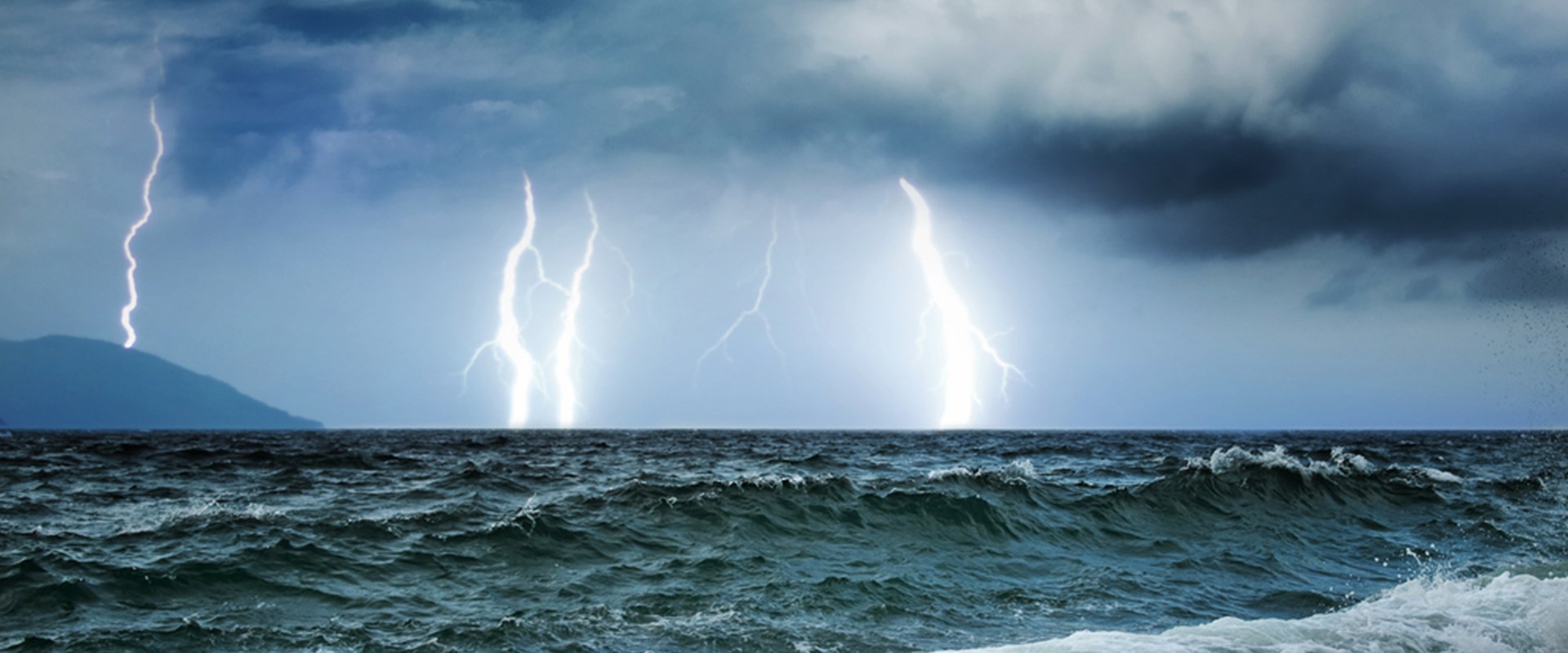 An image of a storm sea with waves and thunder and lighting in the background
