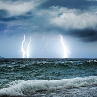 An image of a storm sea with waves and thunder and lighting in the background