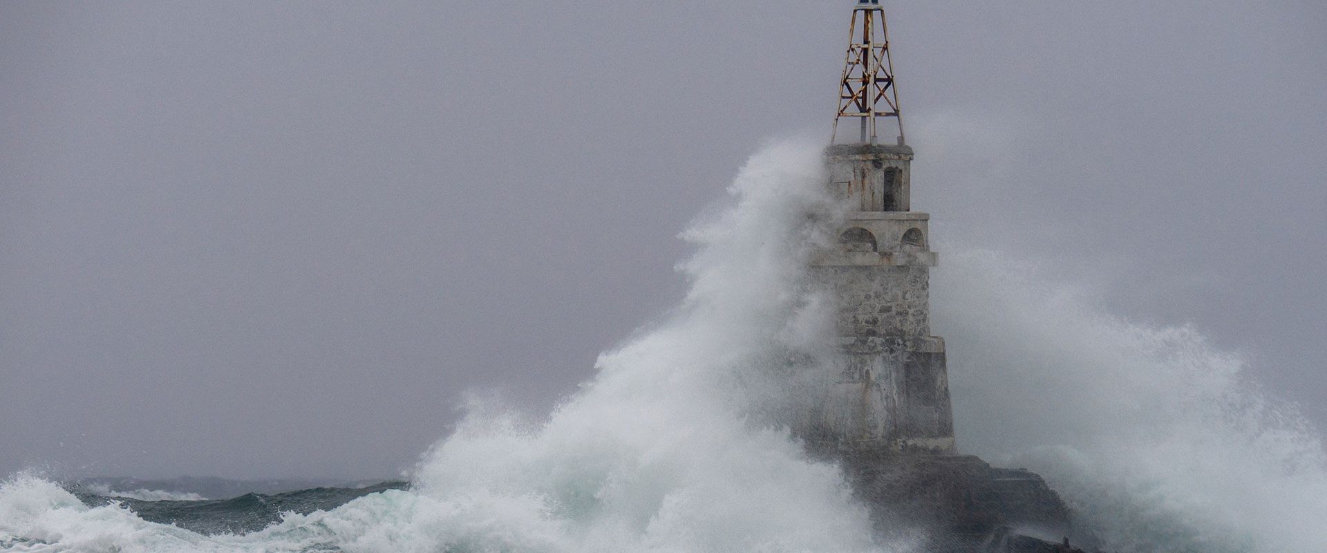 Storm in a port, big wave hitting a lighthouse 