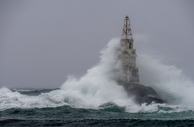 Storm in a port, big wave hitting a lighthouse 